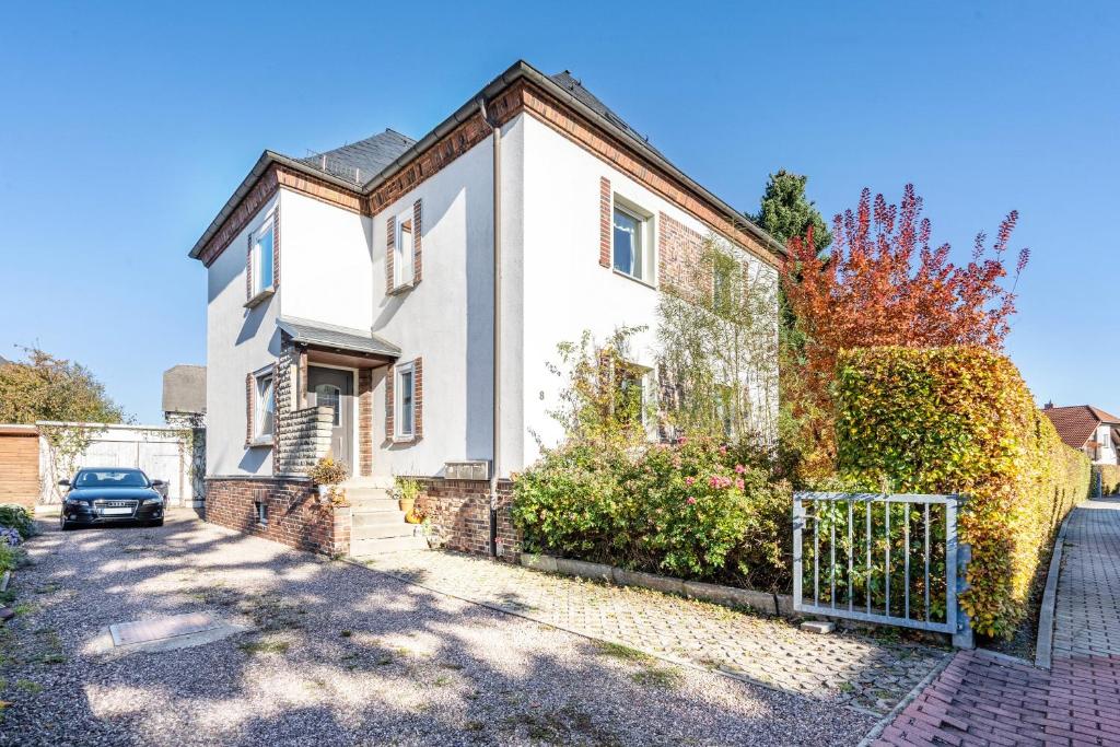 a white house with a fence and a car parked in front at Yvette's Ferienwohnung in Lugau