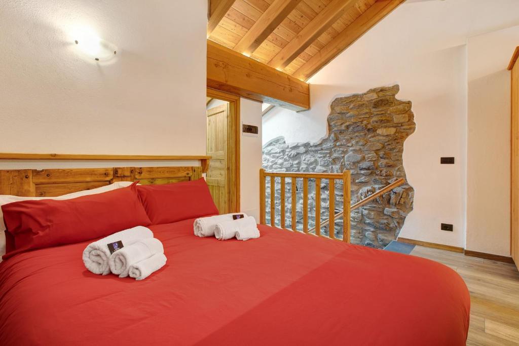 a bedroom with two towels on a red bed at Aux Pieds du Malatra' 1 in Saint-Rhémy-en-bosses