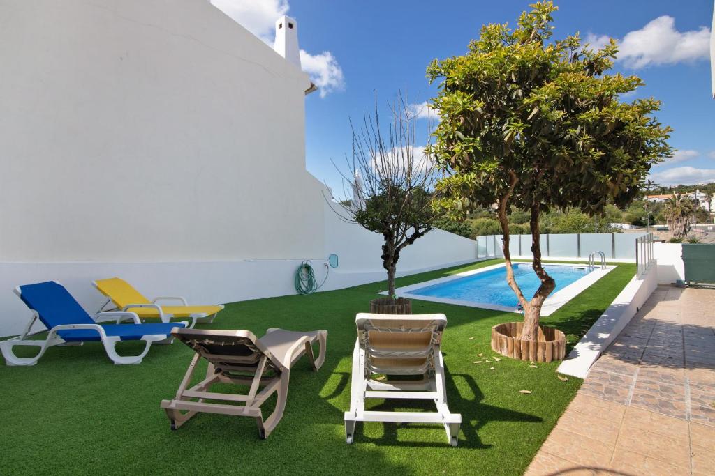 a yard with chairs and a table and a pool at Villa Neves in Albufeira