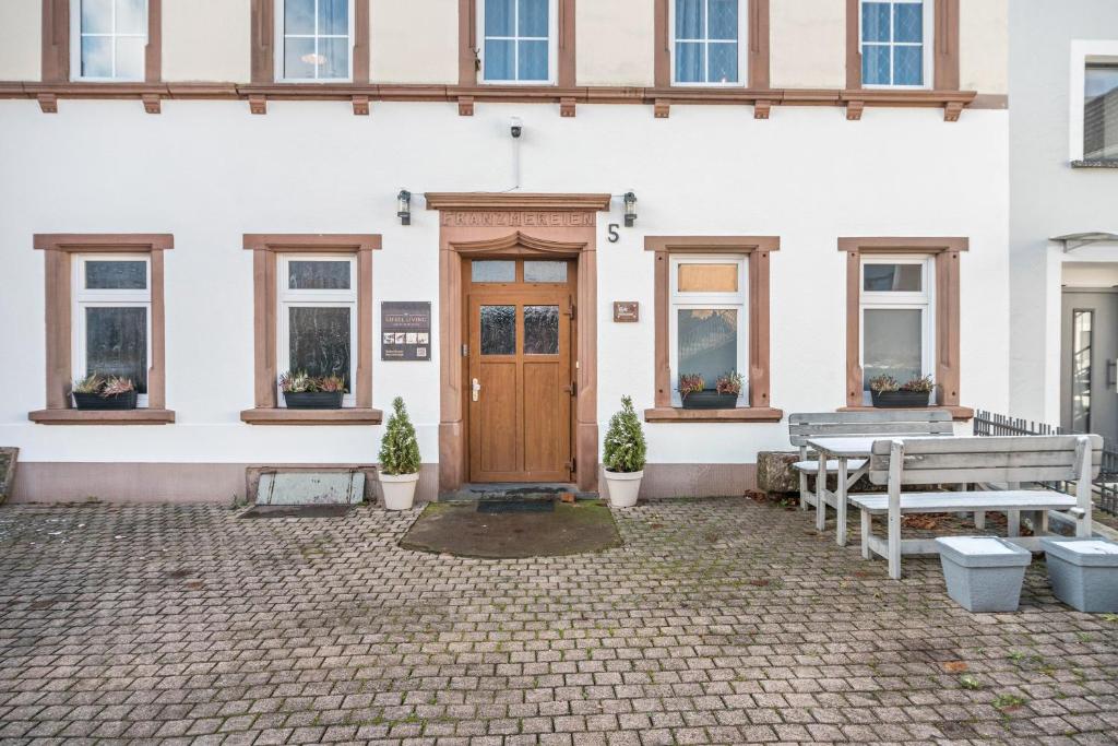a white building with a wooden door and benches at Die Residenz in Neidenbach