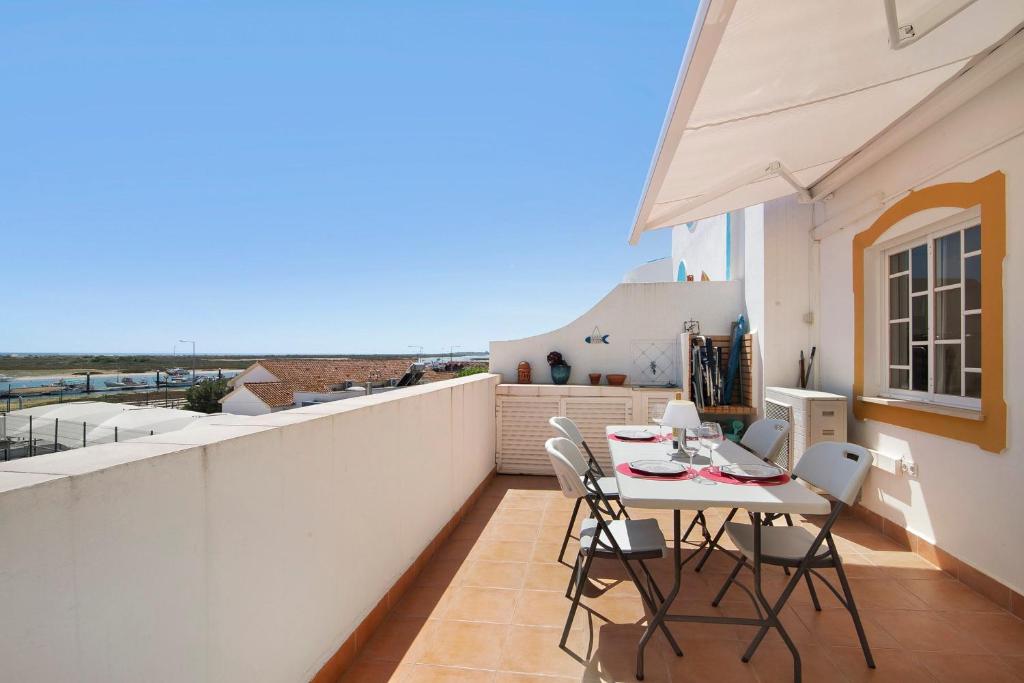 a patio with a table and chairs on a balcony at A Casa de Emy in Cabanas de Tavira