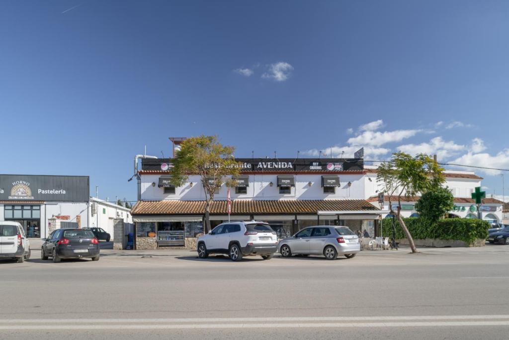 a parking lot with cars parked in front of a building at Hostal Avenida in Conil de la Frontera