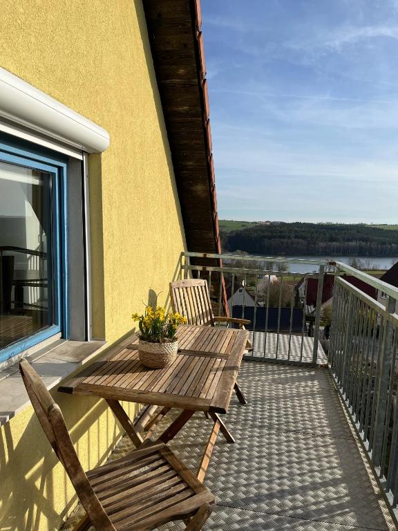 a wooden table and two chairs on a balcony at Galeriewohnung mit Seeblick in Absberg