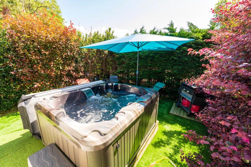 a hot tub with an umbrella in a yard at Appartement de charme - spa privé in Biarritz