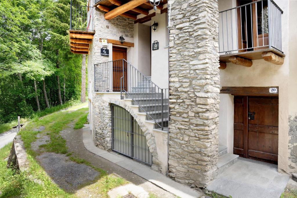 a stone house with a staircase and a door at Arnica Tano di Grich in Cesani