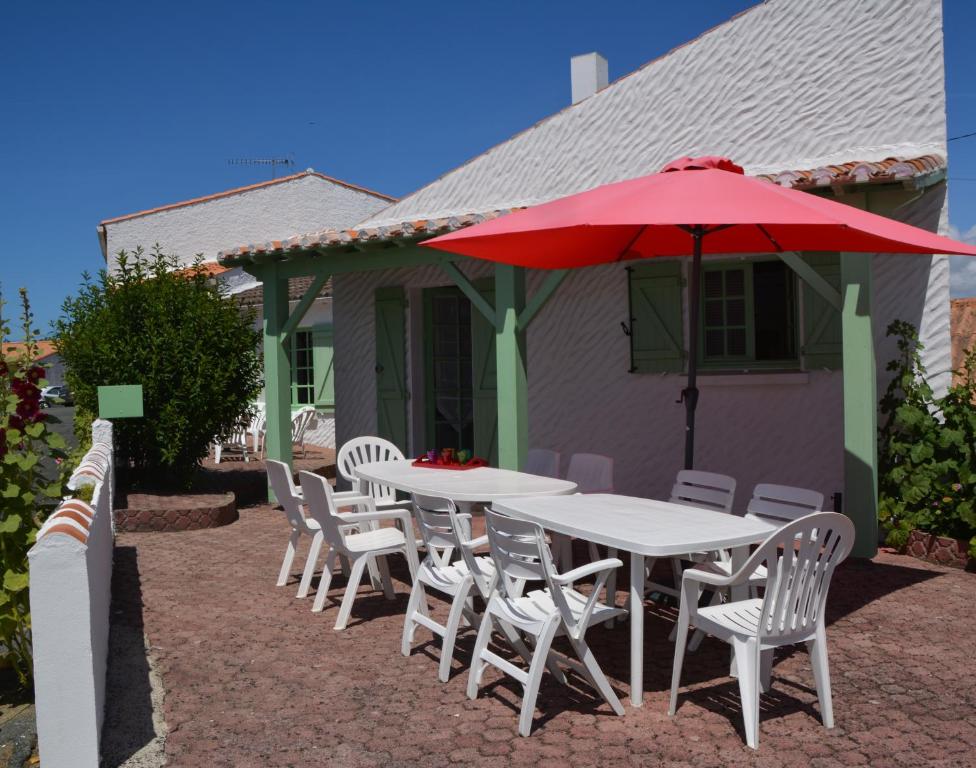 a white table and chairs with a red umbrella at Maison Am Stram Gram in La Tranche-sur-Mer