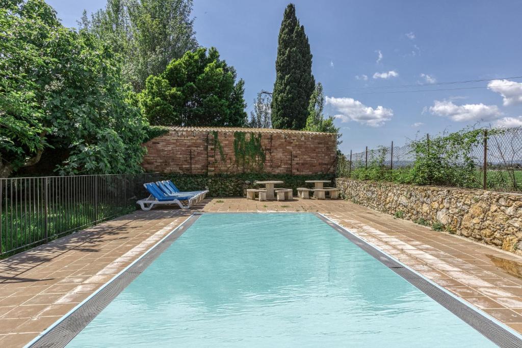 a swimming pool in a yard with a blue chair at Can Casadellà in Serra de Daró