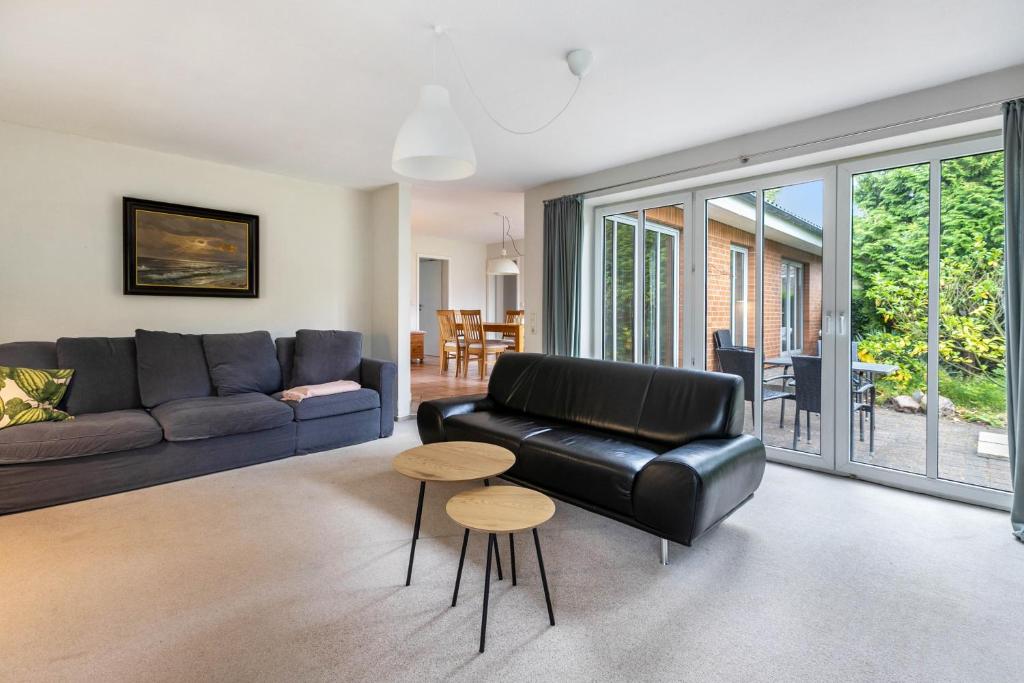 a living room with a black leather couch and stool at Ferienhaus Sprante in Brunsbüttel