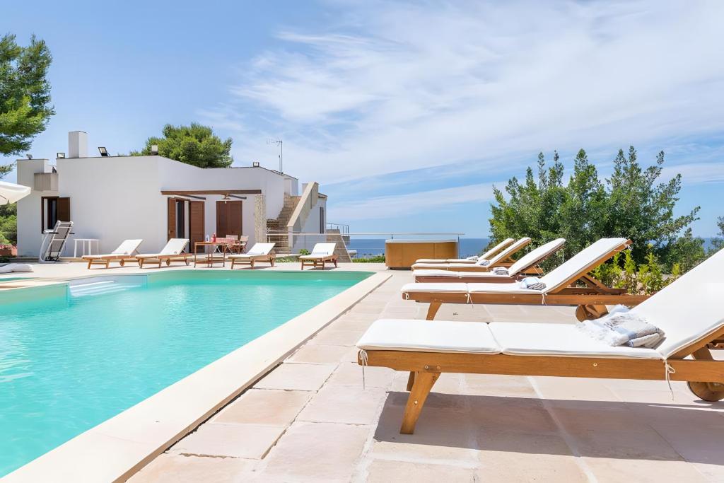 a villa with a swimming pool and lounge chairs at Cala D'Aspide in Santa Caterina di Nardò