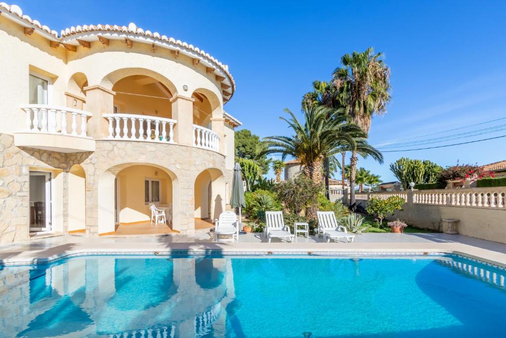 a villa with a swimming pool in front of a house at Villa Cucarres in Calpe