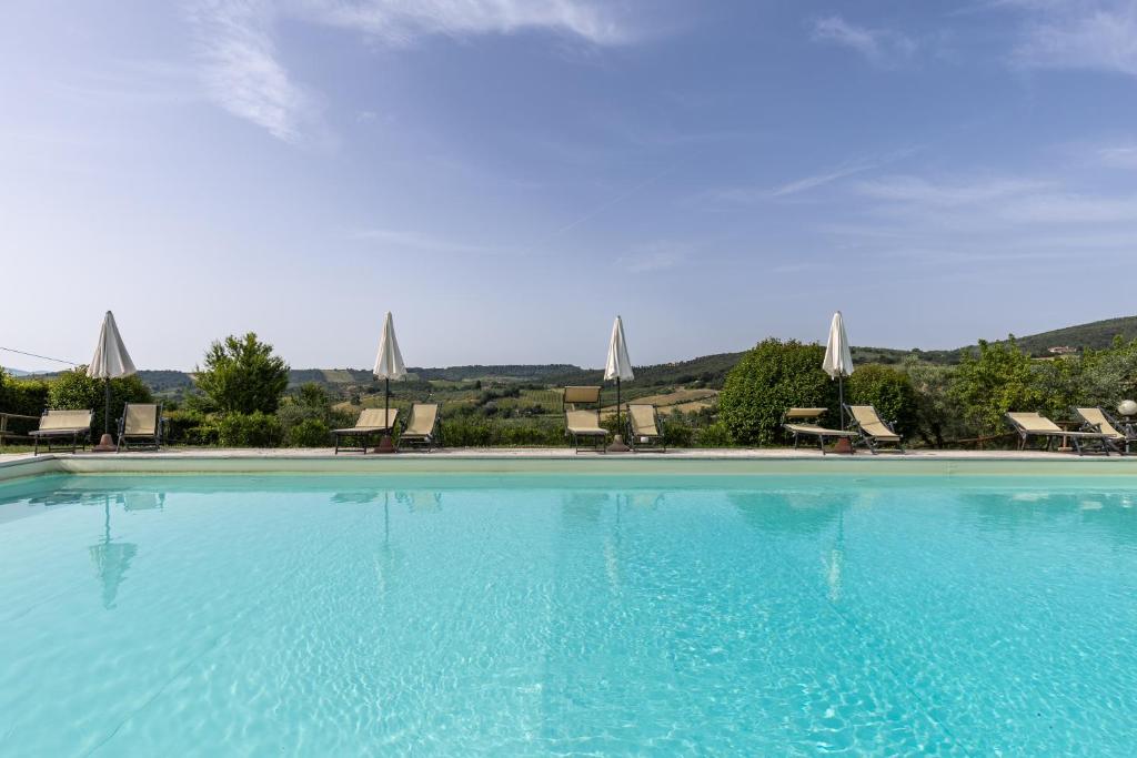 a large blue swimming pool with chairs and umbrellas at Suite Deluxe Torre in San Gimignano