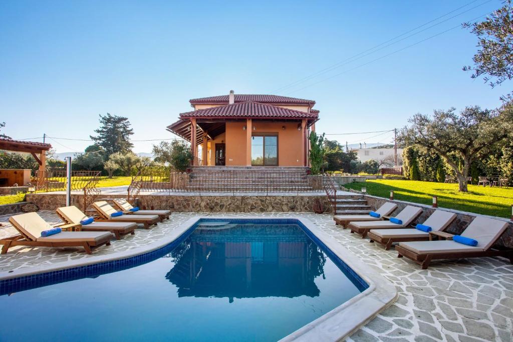 a swimming pool with lounge chairs and a house at Villa Totta in Alikanas