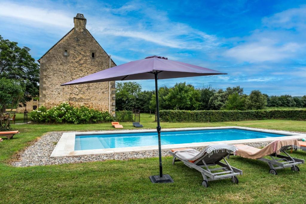 an umbrella and chairs next to a swimming pool at Le Bel Prat in Domme