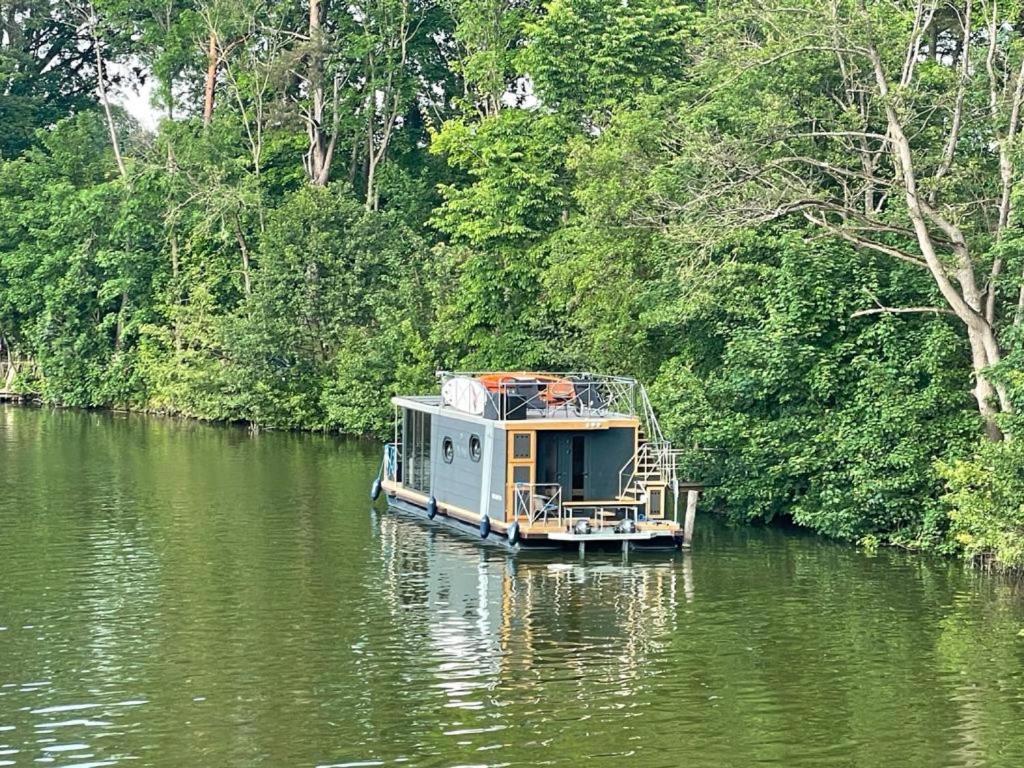 a small boat in the middle of a river at Führerscheinfreies mobiles Hausboot in Rechlin