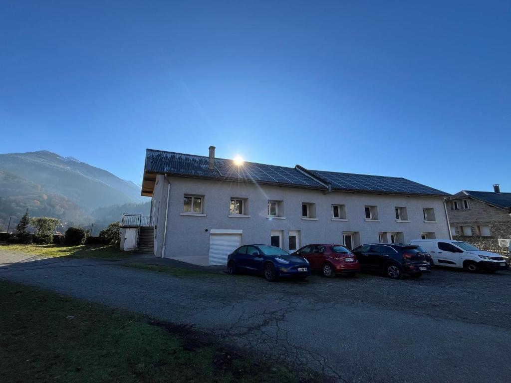a white building with cars parked in front of it at Logis Les Forges in Arvillard