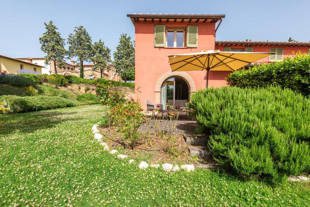 a garden with a house with an umbrella at Chalet Azzurro in Trequanda