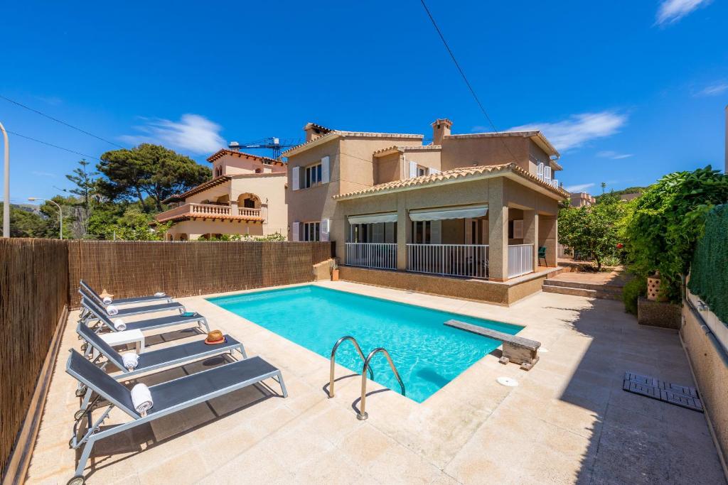 a villa with a swimming pool in front of a house at Villa Paca in Cala Ratjada