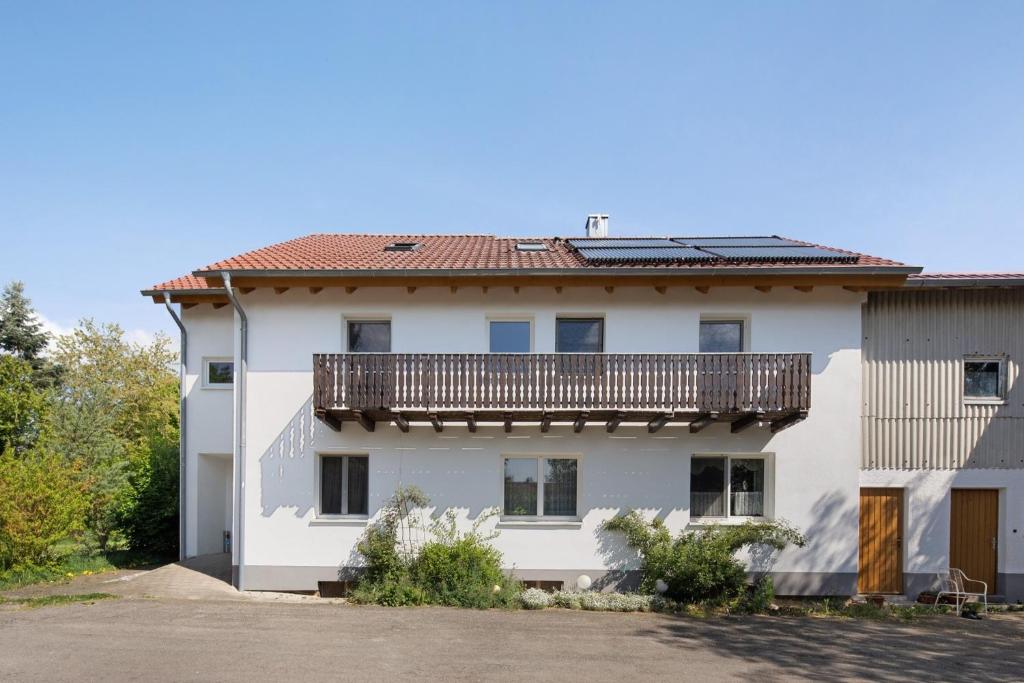 a white building with a balcony on top of it at Ferienwohnungen große Albferien in Heroldstatt