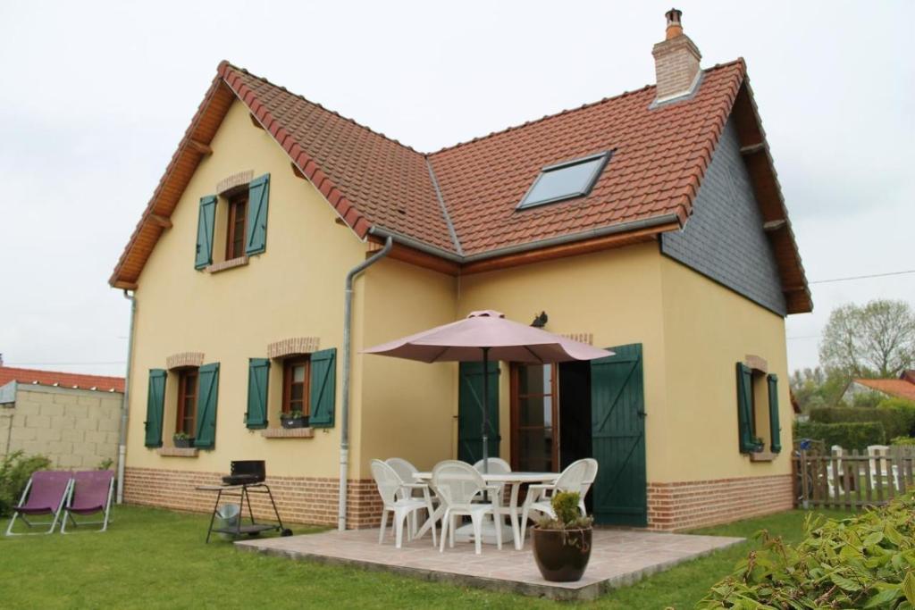 a house with a table and chairs and an umbrella at Gîte La Briqueterie 3 Épis in Quesnoy-le-Montant