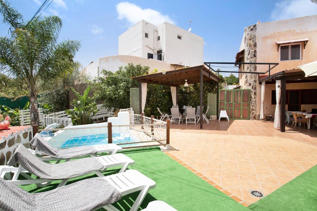 a patio with lawn chairs and a swimming pool at Casa Las Flores in Moya