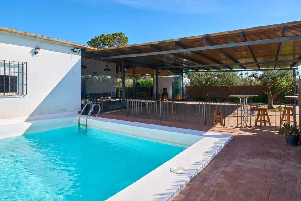 a swimming pool with a pergola next to a house at Casa Rural Olivar de la Marquesa in La Carlota