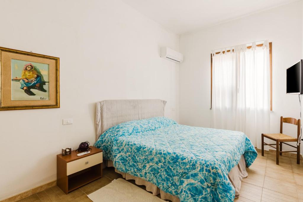 a bedroom with a bed with a blue comforter at Casa Rimedia in Solanas