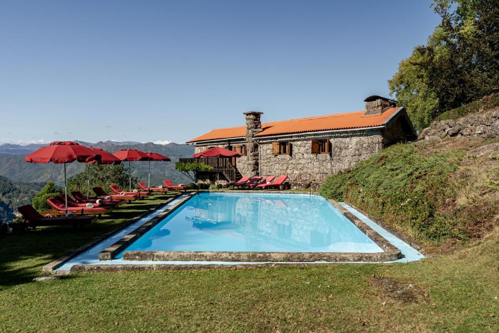 a swimming pool with chairs and umbrellas next to a house at Casa do Gerês in Geres
