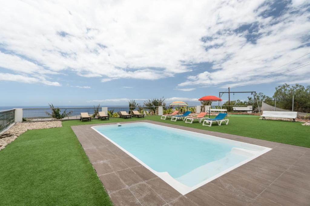 a swimming pool in a yard with chairs and tables at La Atalaya in Adeje