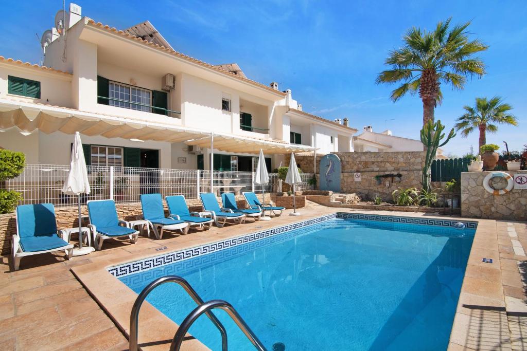 a villa with a swimming pool with blue lounge chairs at Villa Guisado in Albufeira