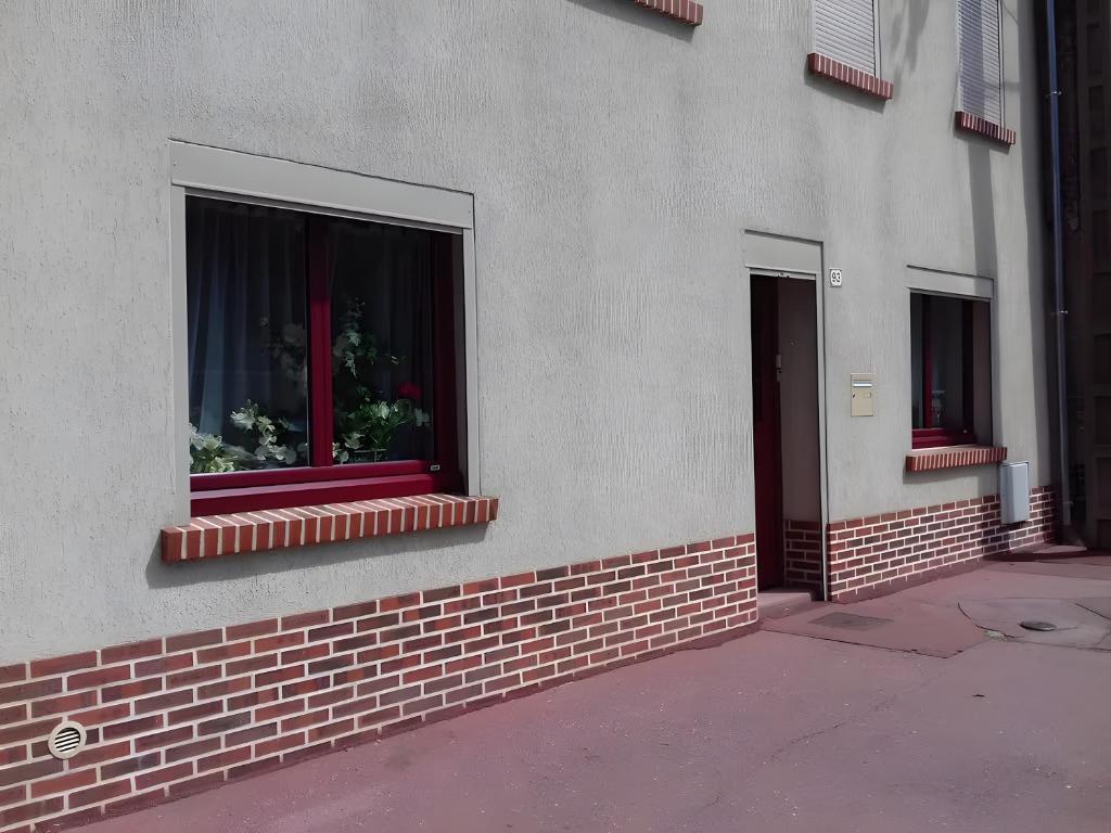 two windows on a building with flowers in them at Les Chambres Des Chtis in Abbeville
