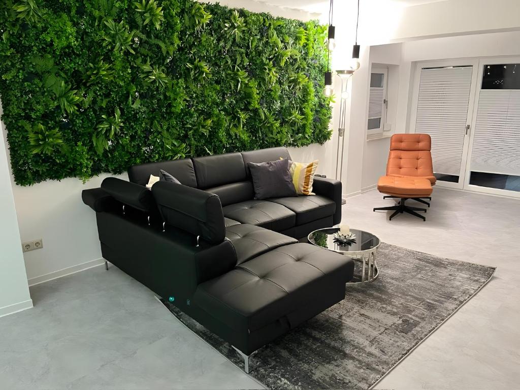 a living room with a black leather couch and an orange chair at Ferienwohnung Oleander in Dresden