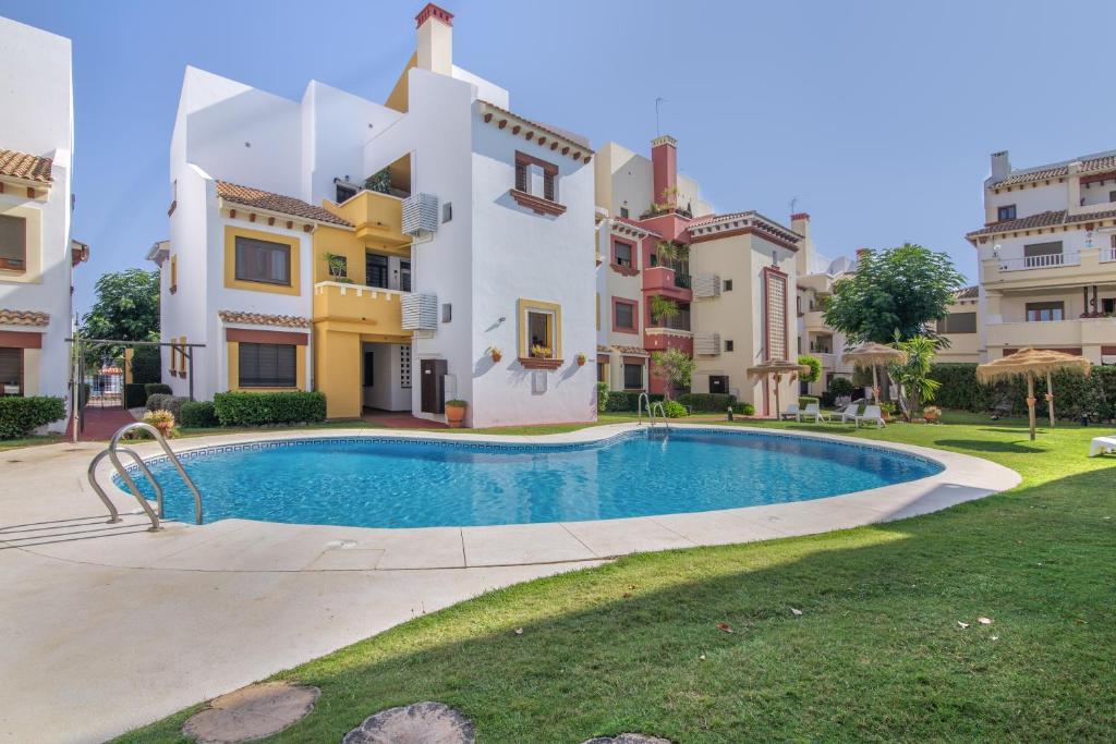 a villa with a swimming pool in front of a building at Saadia Golf in Huelva