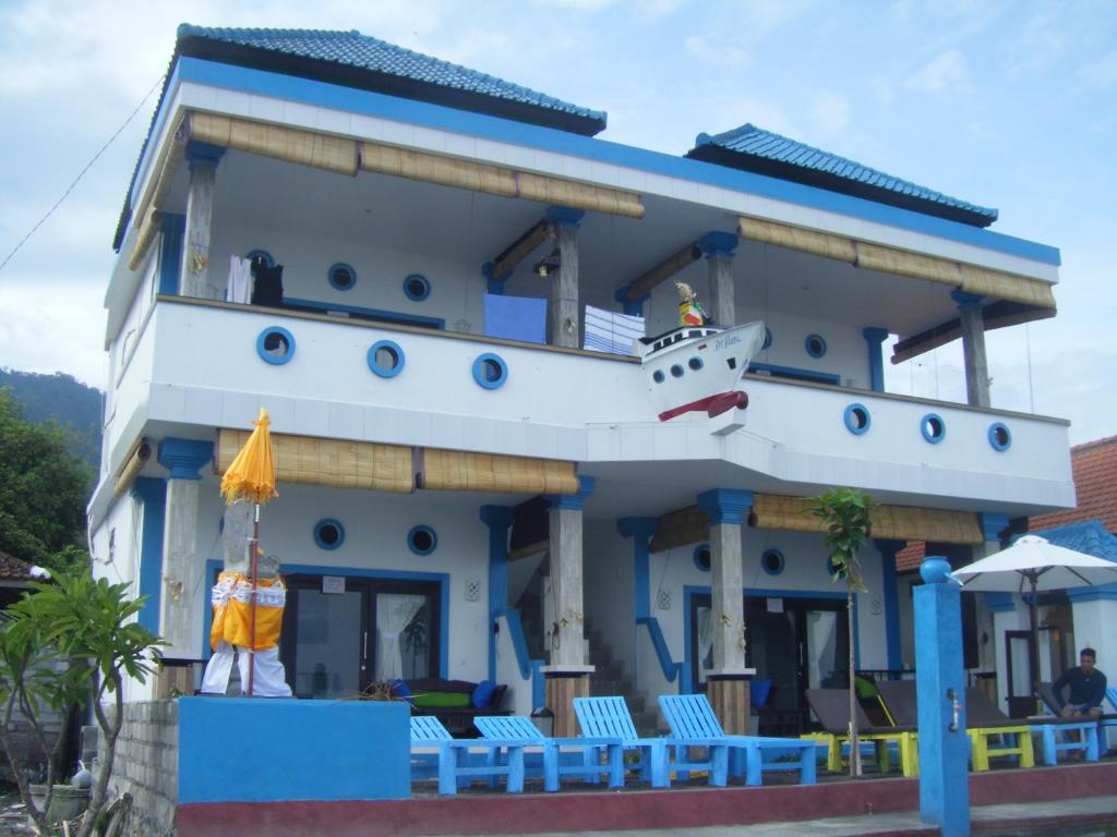 ein blau-weißes Gebäude mit Stühlen und einem Sonnenschirm in der Unterkunft De Adema Guesthouse in Amed
