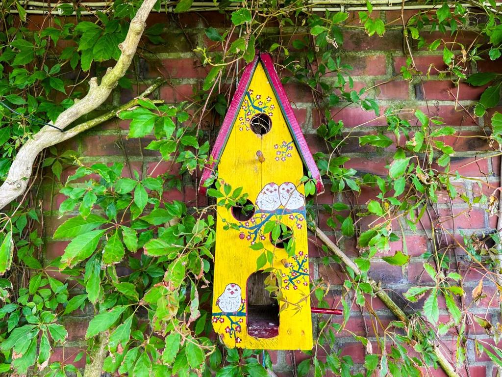 a yellow and pink object is hanging on a brick wall at Relas Ferienwohnungen - Spatzennest in Nordstrand