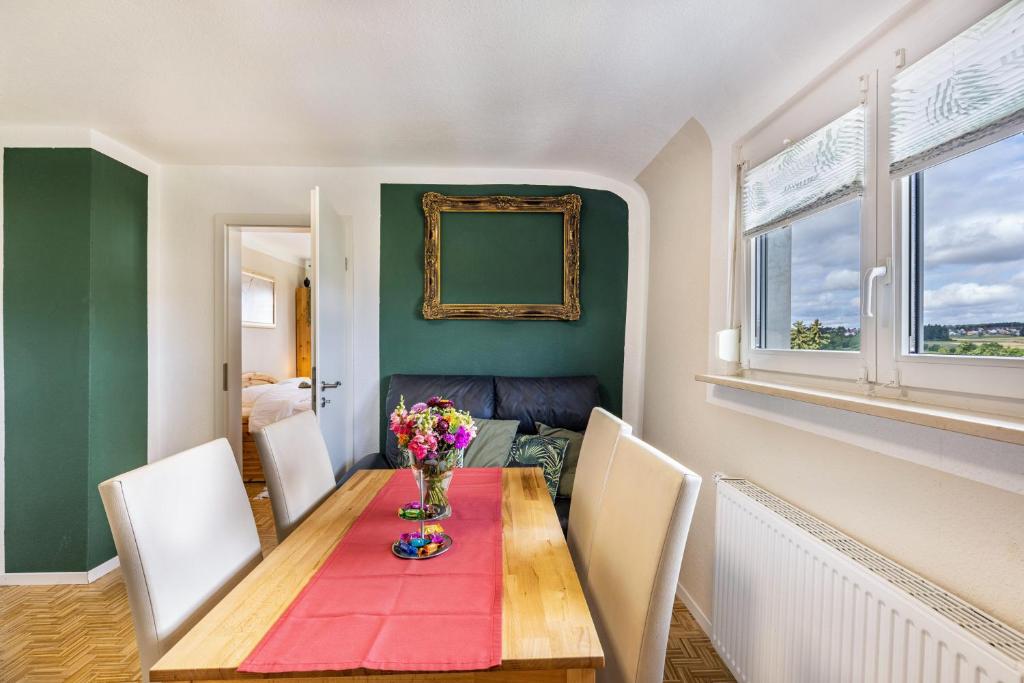 a dining room with a table with flowers on it at Baumelt Ferienwohnung in Hechingen