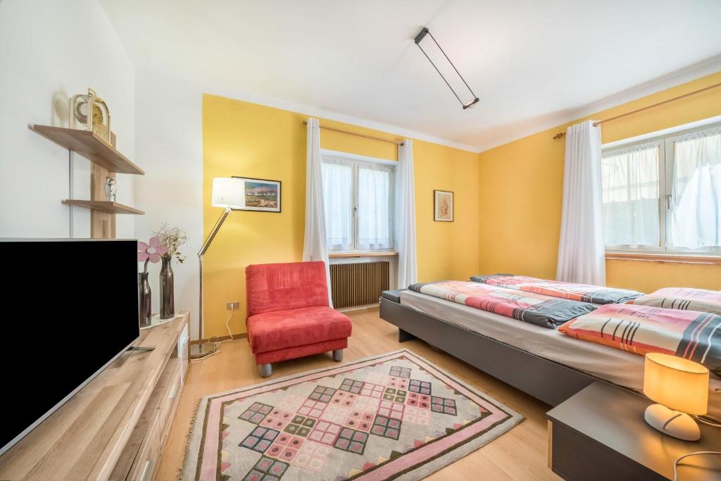 a bedroom with a bed and a red chair at Apartement Oase in Lana