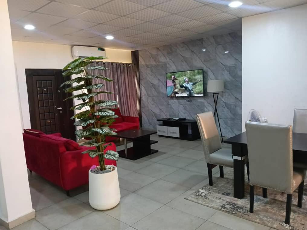 a living room with a red couch and a palm tree at Derins court in Ibadan