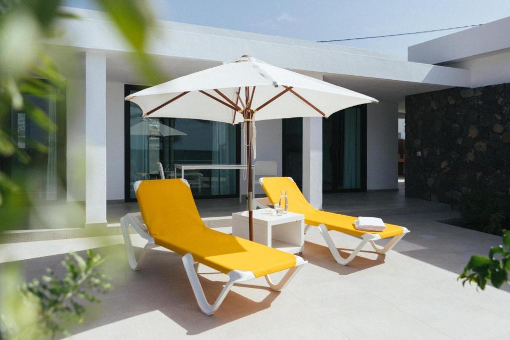two yellow chairs and an umbrella on a patio at Casa Agua Nueva 53 in Frontera