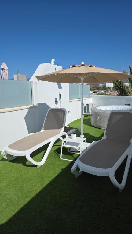 a pair of chairs and an umbrella on a lawn at BlumLuxury Apartment in San Bartolomé
