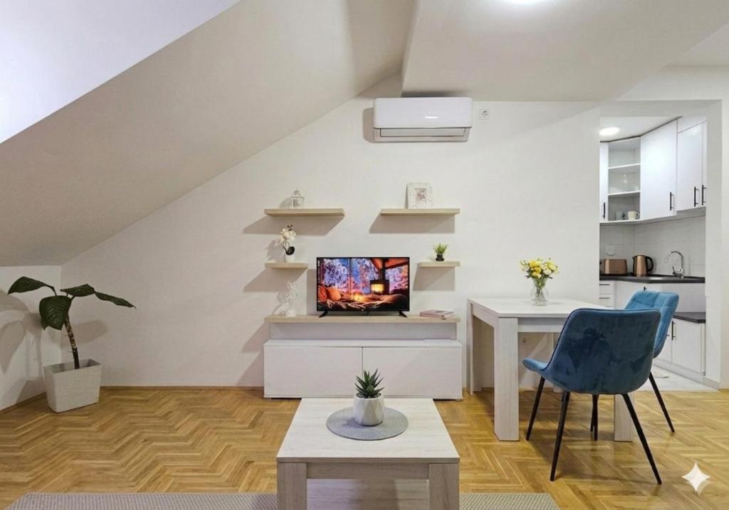 a living room with a tv and a blue chair at Apartman Panorama 2 in Požarevac