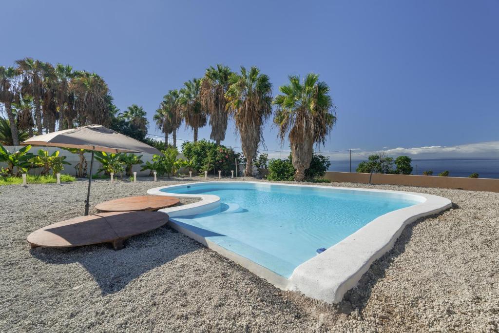 a swimming pool on the beach with two chairs and an umbrella at La Casa del Caballo in Adeje