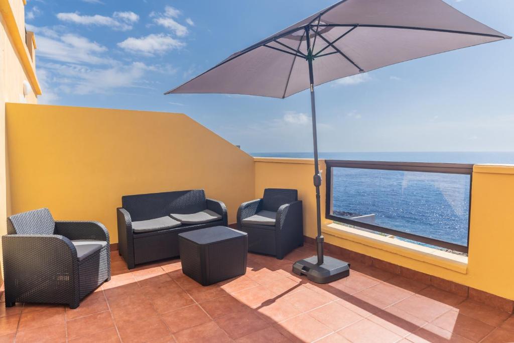 a balcony with two chairs and an umbrella at Costa Fortuna in Poris de Abona