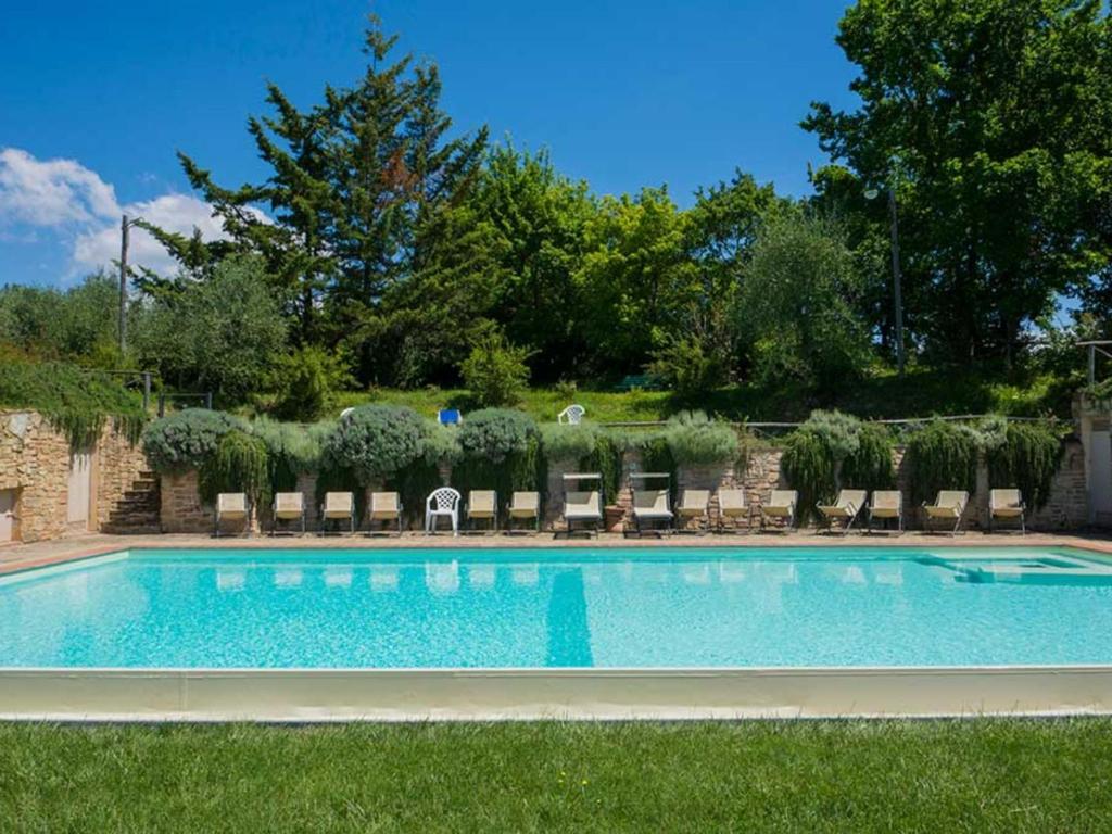 a large swimming pool with lounge chairs and trees at Appartamento il Melo in Grassina