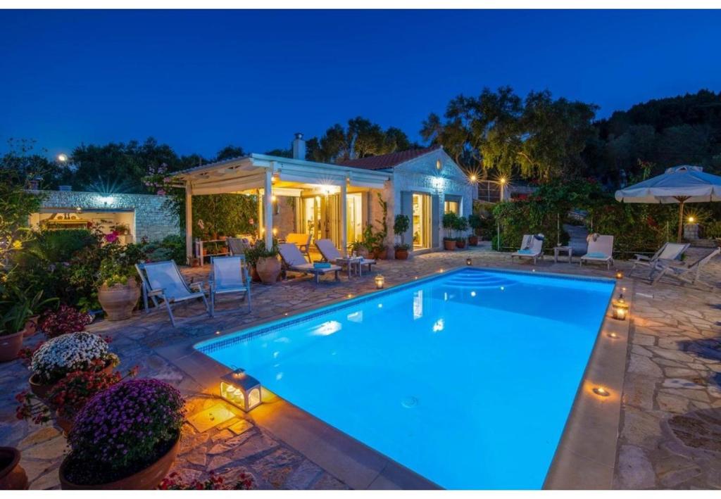a swimming pool in a backyard at night at Villa Aloni in Lákka