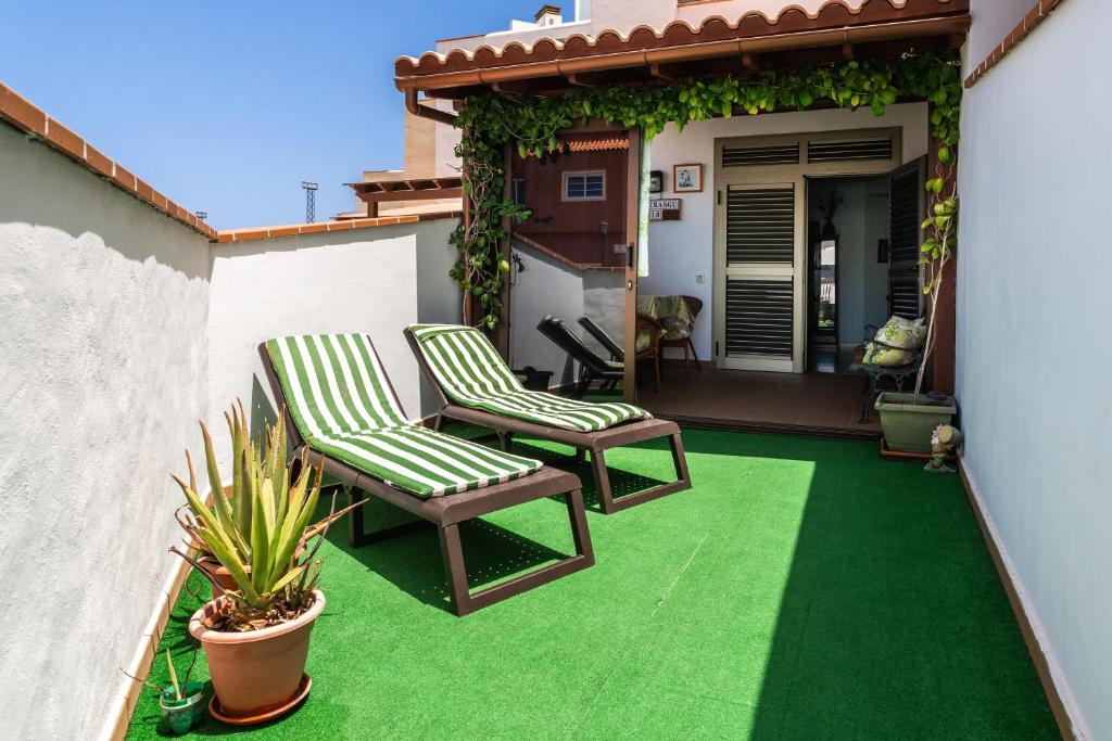 a patio with two chairs on a green lawn at Apartamento el Carmen in El Cotillo