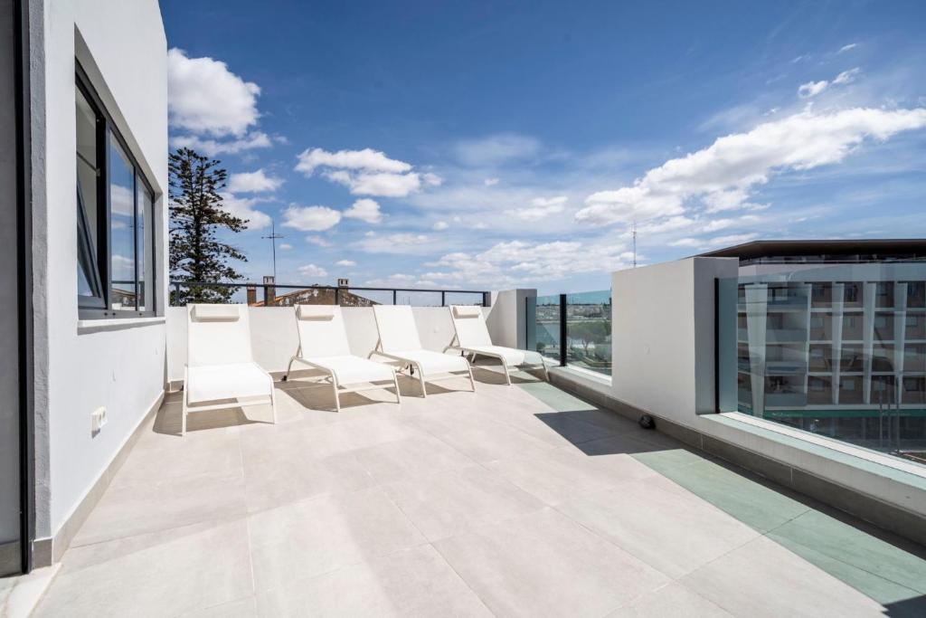 a balcony with white chairs on top of a building at Ptm Arade View Penthouse T3 Duplex in Portimão