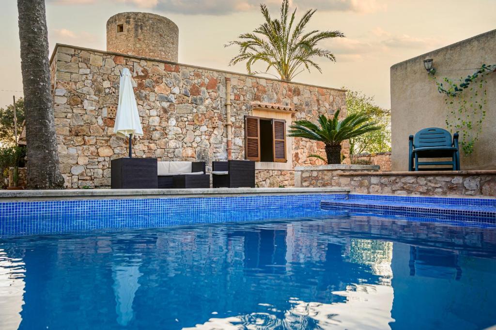 a swimming pool in front of a house with a building at Villa moli de ca n'orell in Santanyi