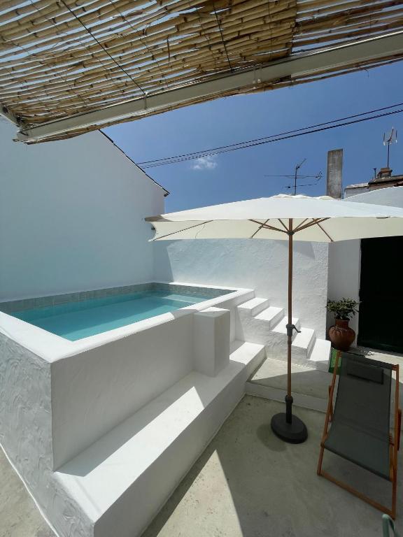 a swimming pool with an umbrella and a table at A Casa dos Raminhos in Vila de Frades
