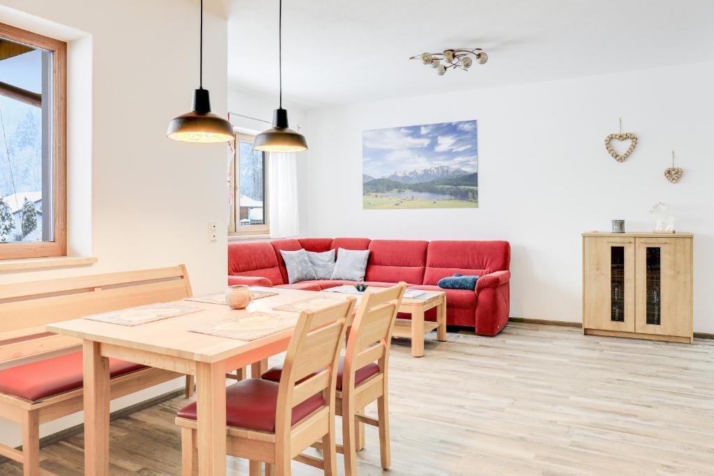 a living room with a table and a red couch at Ferienwohnung Geroldsee in Garmisch-Partenkirchen