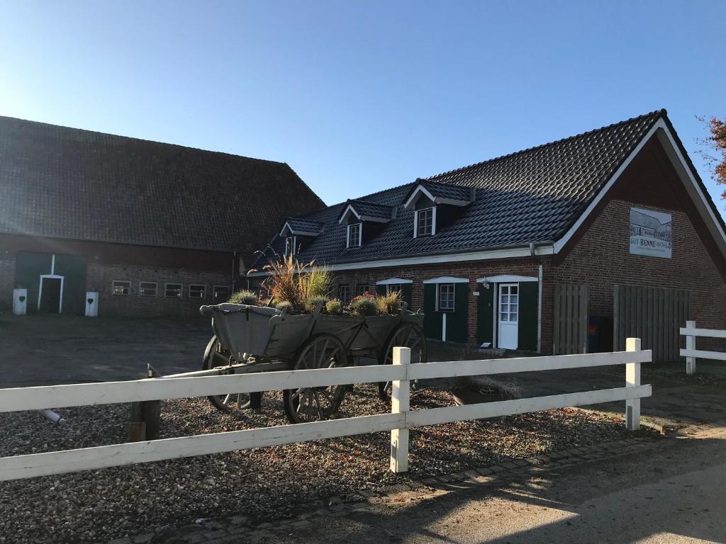 a farm building with a fence and a tractor with plants at Gut Bennewohld in Heide